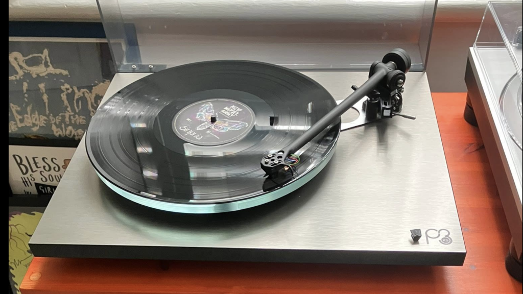 Rega turntable installed in customer listening room alongside amplifier and vinyl record collection